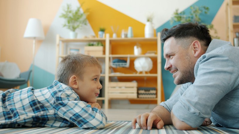 Parent and child lying on a striped rug in a bright family living room