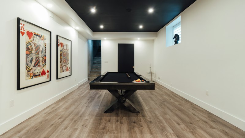 Finished basement rec room with wood-look waterproof flooring and a pool table