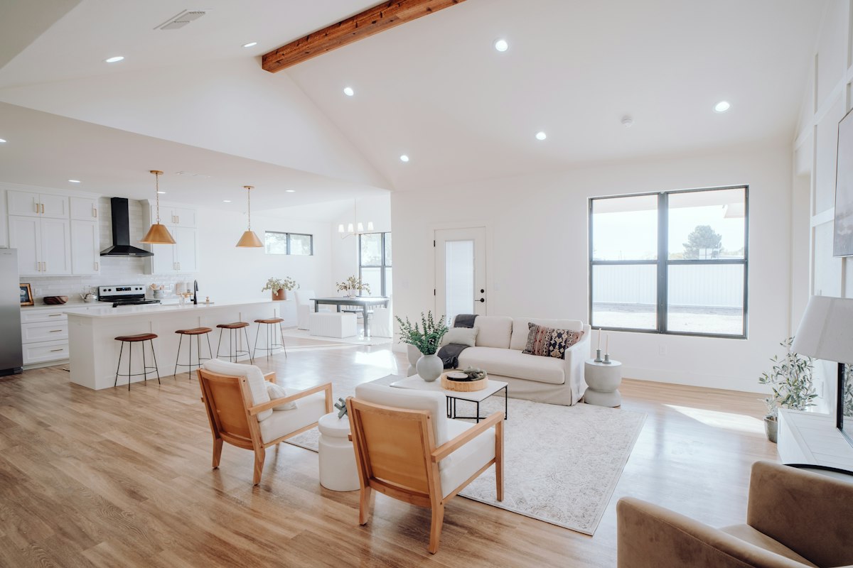 Open floor plan with light wood flooring running from the living room into the kitchen, with an area rug under the seating