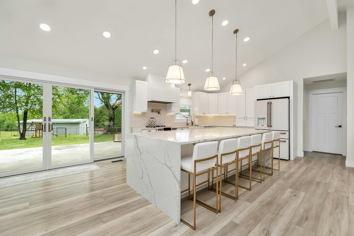 White kitchen with a marble island and light gray wood-look plank flooring