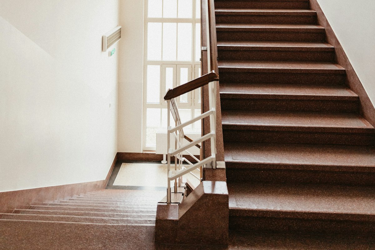 Straight staircase with brown carpet on every tread and a wood ceiling above