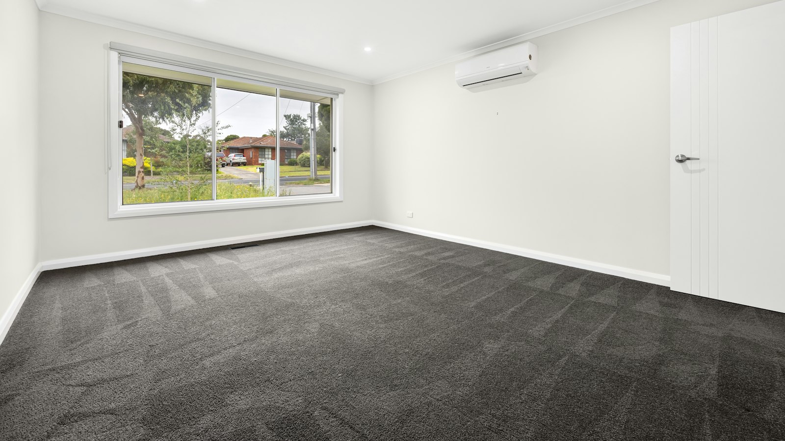 Empty room with new charcoal wall-to-wall carpet showing fresh vacuum lines across the pile