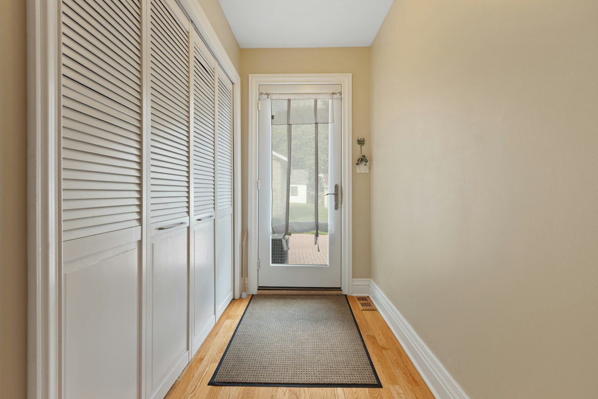Walk-off mat inside a front door protecting a hardwood entry hallway from grit and snowmelt