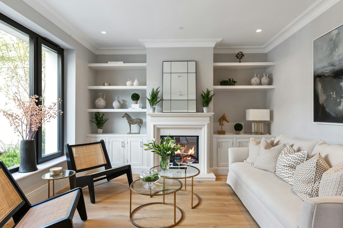 Staged living room with light wood flooring, a fireplace and built-in shelves ready for a home listing