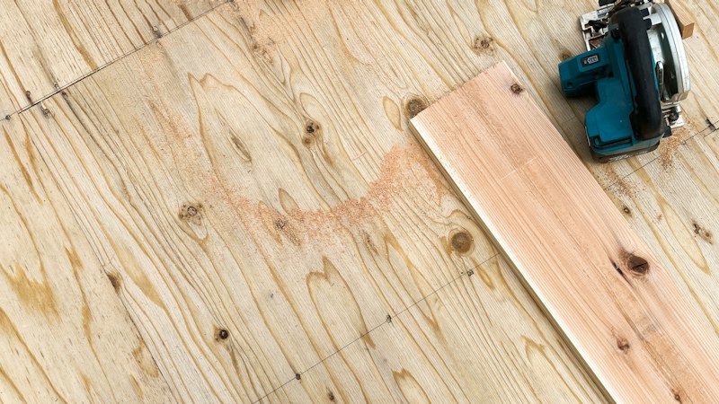Wood plank and circular saw resting on a plywood subfloor during a flooring install