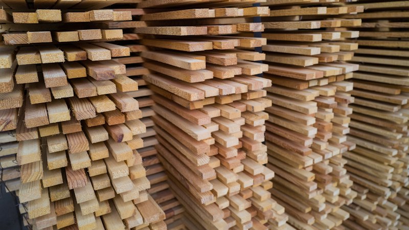 Tall stacks of wood boards stored with airflow between the rows