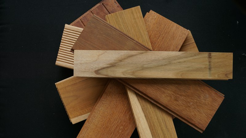 Fan of hardwood flooring samples in a range of wood species and tones on a black background