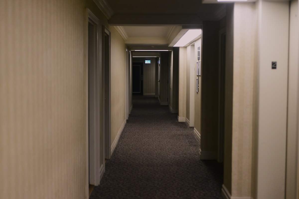 Long hallway with dark wall-to-wall carpet, the kind of traffic lane that wears first