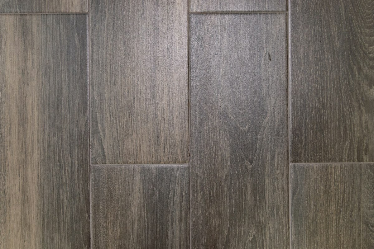 Close-up of gray wood-look plank flooring with staggered end joints and visible grain texture