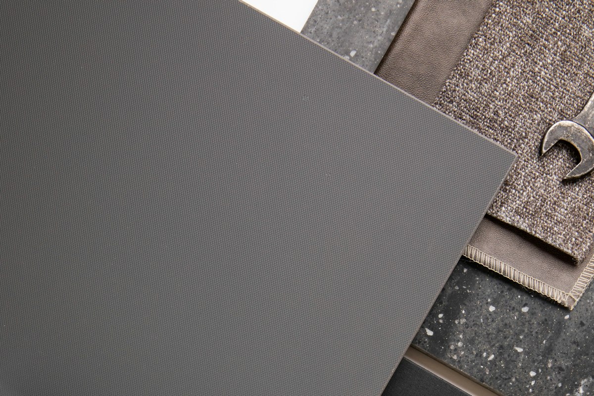 Gray flooring, stone and textile material samples laid out side by side for comparison
