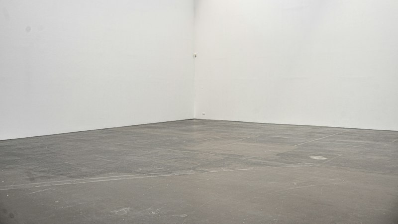 Empty room with white walls and a bare gray concrete slab floor
