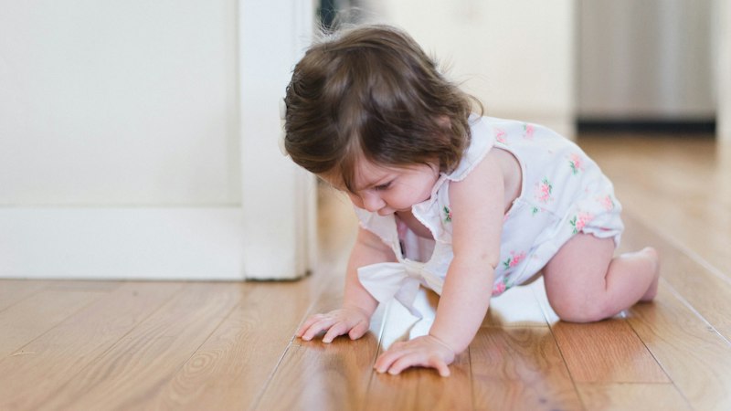 Toddler crawling on a hardwood floor in a bright home