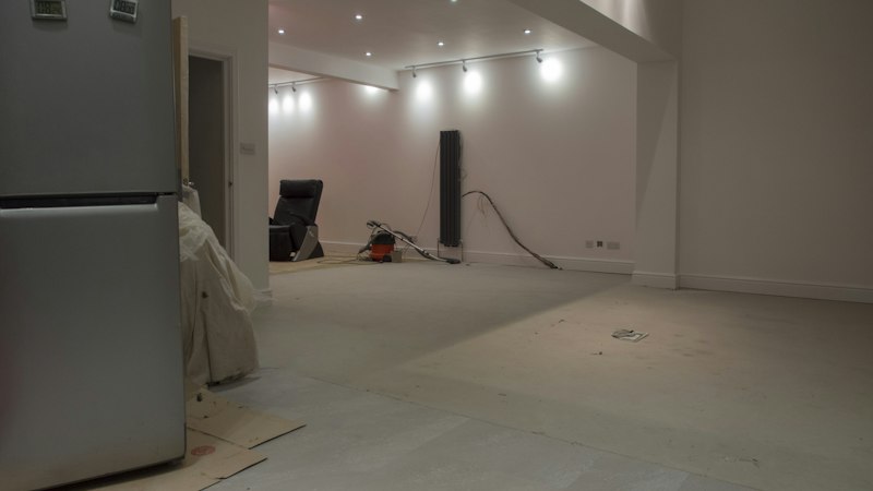 Room cleared for flooring installation with furniture removed and protective paper on the floor